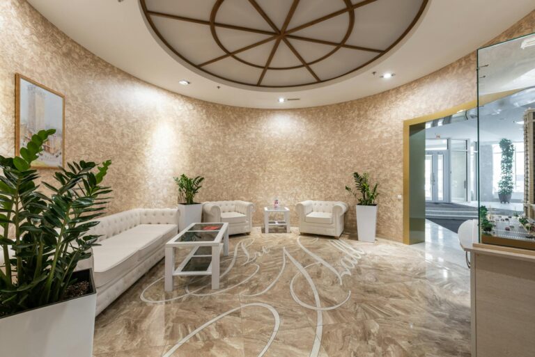 Interior of spacious lobby with comfortable white sofa and armchairs placed in contemporary hotel in daylight