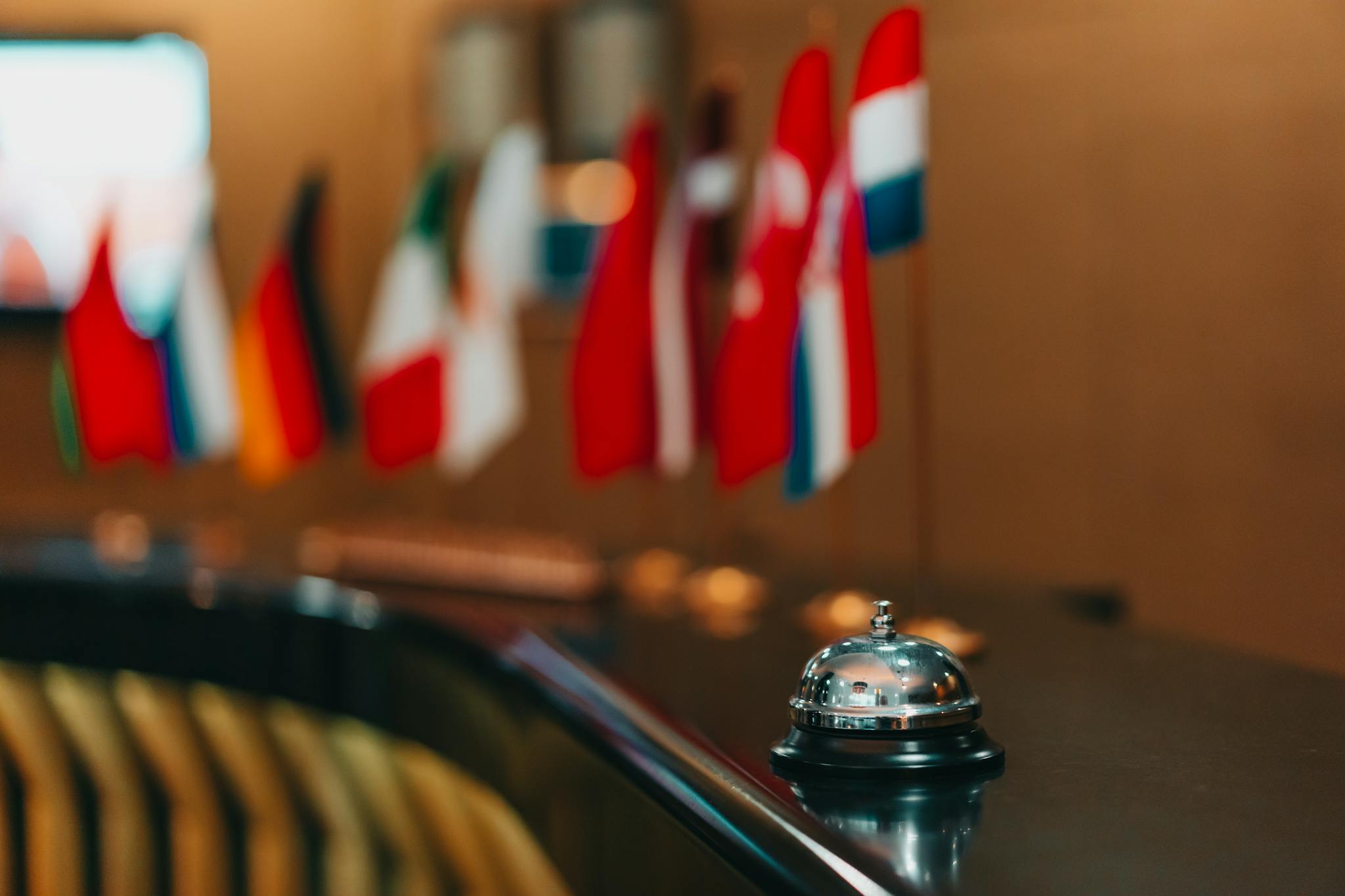 Sophisticated hotel lobby with a reception bell and array of international flags in focus.